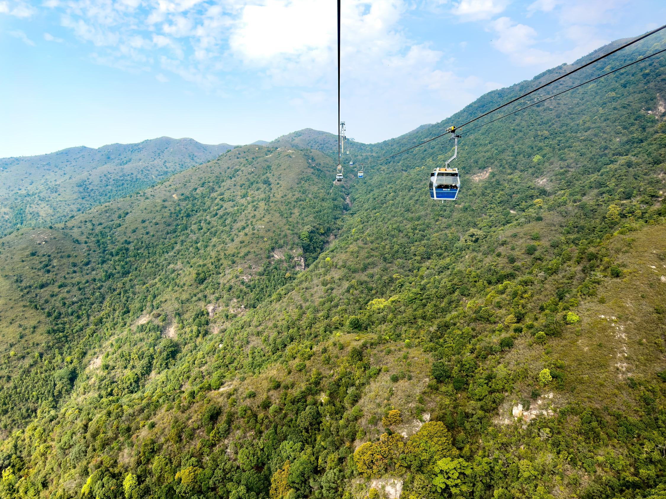 Blick aus der Seilbahn entlang der Seile. Diesmal überall nur Teilweise mit Bäumen, teilweise nur mit Gras bewachsene Berge. Die entfernung bis zum nächsten Mast dürfte fast 1km sein.